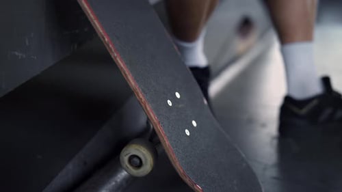 Young hipster man resting with skate board at urban skate park in slow motion