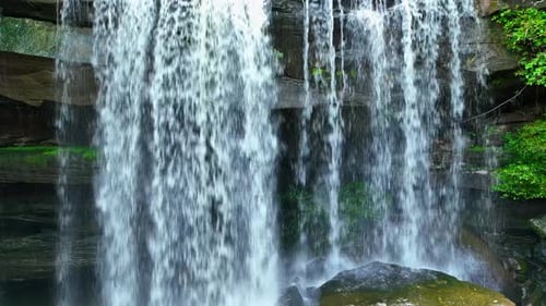 A breathtaking waterfall cascading through a lush forest. Drone view.