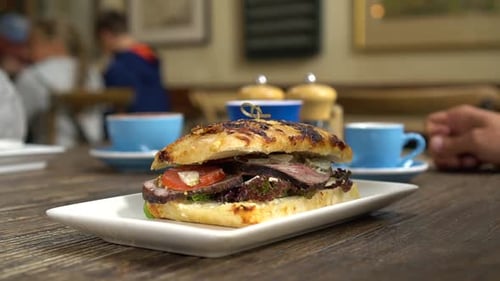 SLOWMO - Beef sandwich for breakfast and coffees in background in stylish cafe