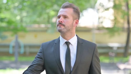 Man in Suit Shielding Eyes Outdoors