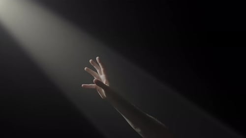 Hand Reaching into the Light in the Darkness