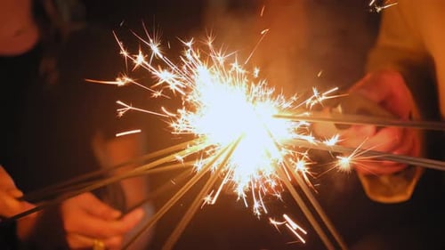 Close Up View of Hands Holding Sparklers Group of Friends Celebrating Wedding Waving Sparkler