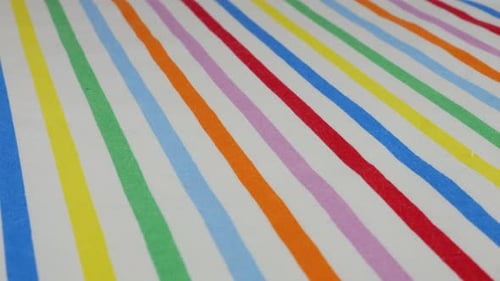 Top view of white cotton fabric with rainbow stripes rotated on the display case. Textile background