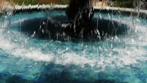 Close-up of water pouring out of a round water fountain in slow motion at 96fps.