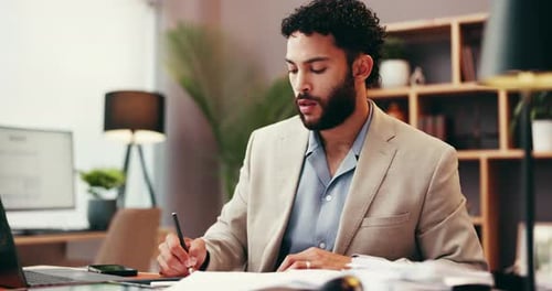 Man Working at Desk Writing Notes in Office
