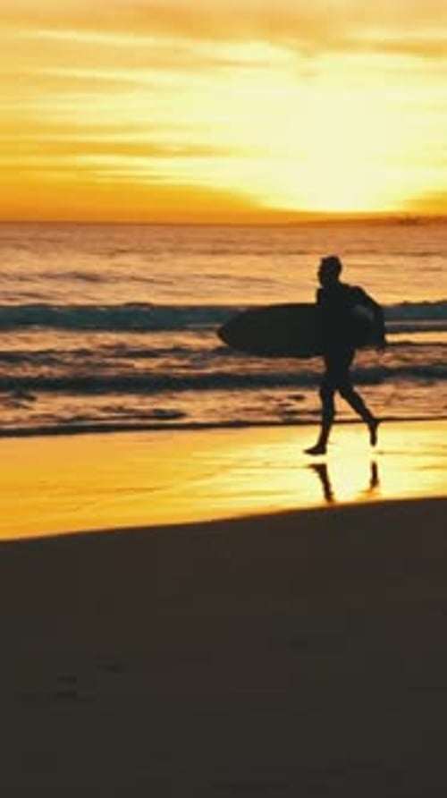 Surfer Silhouette Running on Beach at Vibrant Sunset
