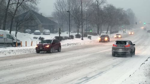 Autos fahren im Schneesturm auf der Winterstraße