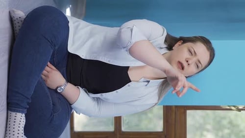Young Woman Sits on Floor in Pain