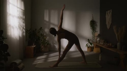 Silhouette d'une passionnée de yoga faisant du Trikonasana à la maison