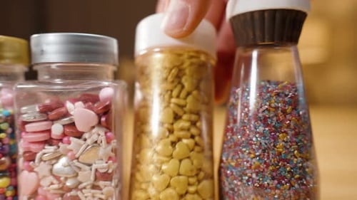 Close-up slider, a pastry chef choosing sugar sprinkles for decorating pastries, various shapes.