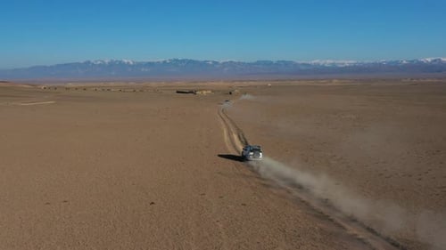 Aerial tracking drone shot of a car caravan traveling in the Charyn Canyon, Kazakhstan