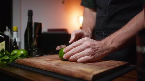 Watch as a mixologist elegantly slices fresh lime for cocktails in a cozy home bar. Perfect for culi