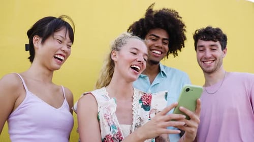 Smiling Friends Look at Phone in front of Wall