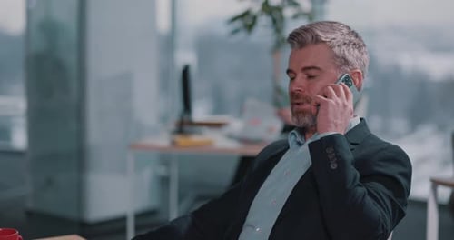 Businessman Talking on Phone While Using Laptop