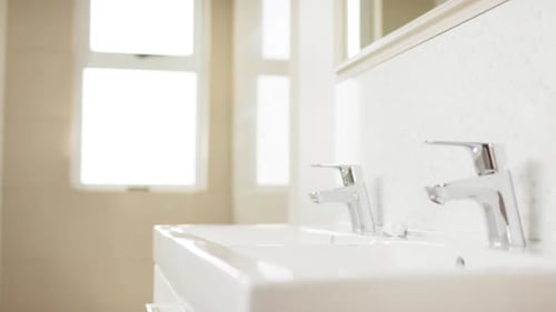 Close up of basin and chrome taps in bathroom, slow motion