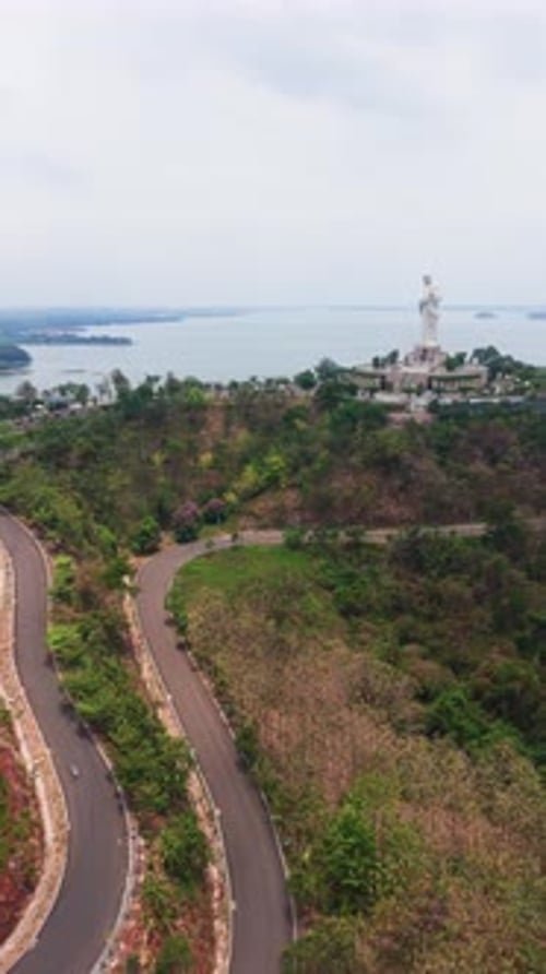 Une photo verticale montre le lac Tri An à Dong Nai, au Vietnam. La route sinueuse passe par le vert