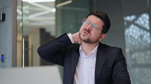 Businessman Experiencing Neck Pain And Discomfort At Office Desk