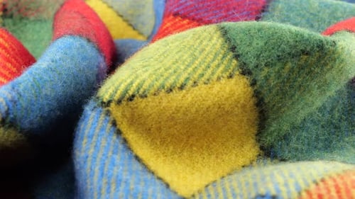 Close-up view of the soft folds of the bright textured multicolored wool fabric rotated
