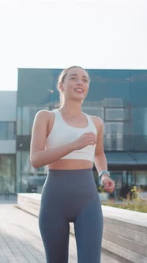 Athletic Runner Woman Looks at Smartwatch Device Fitness Bracelet Checking Heart Rate in City Park