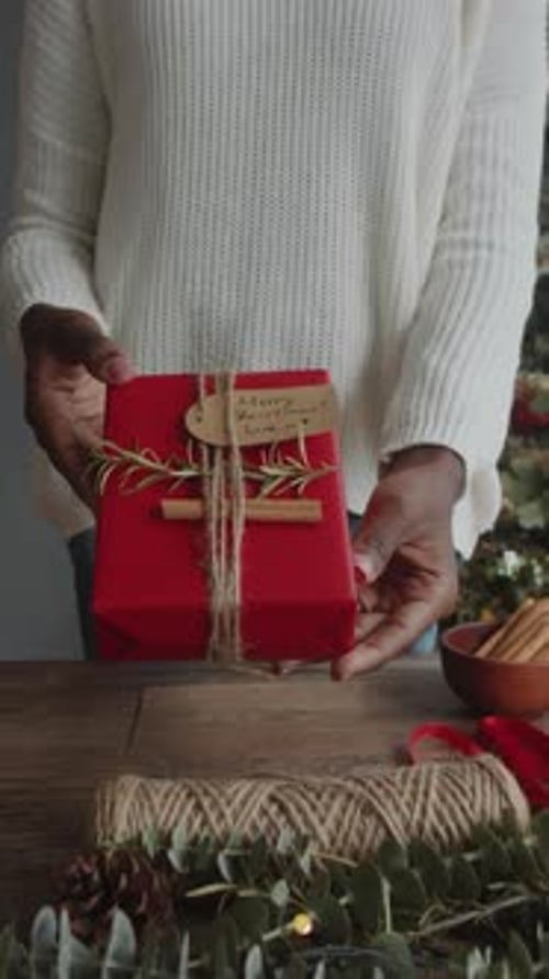 Hands Hold Beautifully Wrapped Red Christmas Gift