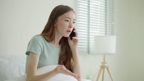 Frustrated Woman Talking on Phone in Bedroom