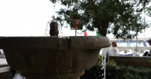 Jets of water flow from the stone bowl of the fountain against the backdrop of the port