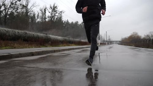 Strong Athlete in Sportswear Jogging Along Trail at Cloudy Day Young Sportsman Running Along Asphalt