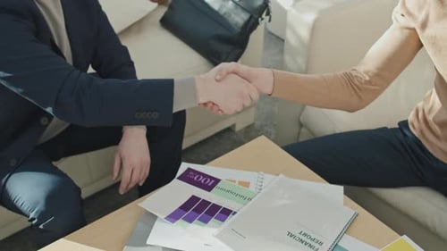 Professional Handshake Over Financial Documents in Office