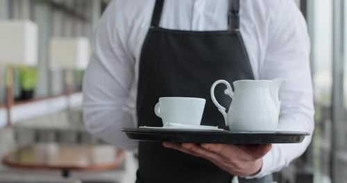 Close Up Waiter and Coffee on a Tray Walking to a Customer in or Restaurant Cafe Man and Woman