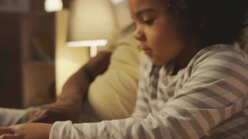 Child and Adult Reading Together on Couch at Night