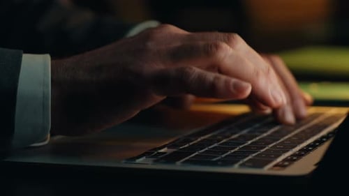 Man Typing on Laptop Keyboard Close Up at Night