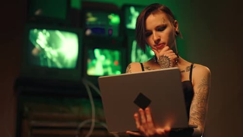 Mulher tatuada, hacker, trabalhando com laptop no porão à noite, crime cibernético, senhora de estilo alternativo