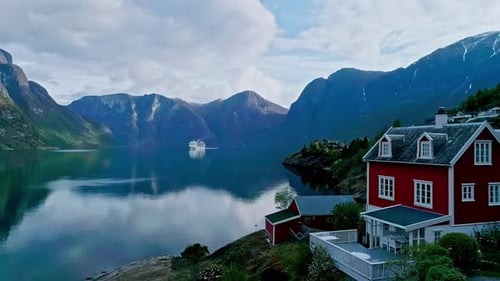 Scenic view of Aurland, Norway with a red house by the fjord and mountains in the background