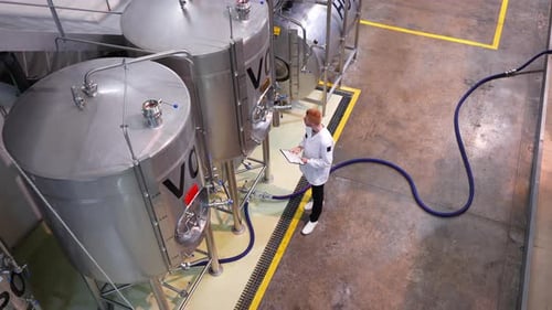 Brewery Worker Inspecting Fermentation Tanks During Beer Production