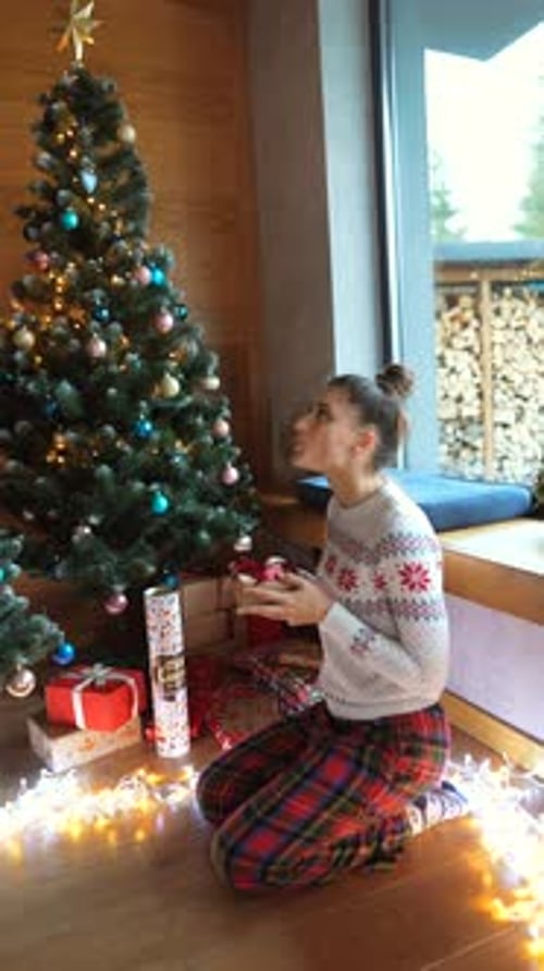 Woman Opening Christmas Gifts by the Trees