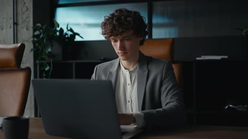 Young Adult Working on Laptop in Modern Office