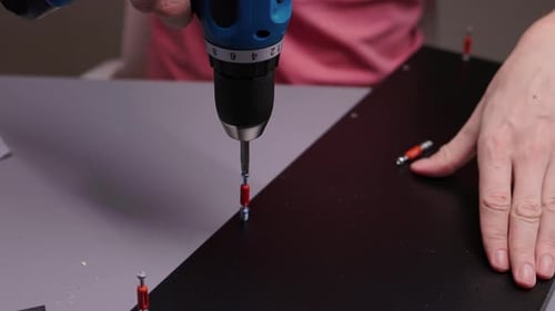 Assembling Dark Furniture with Cordless Screwdriver Close Up