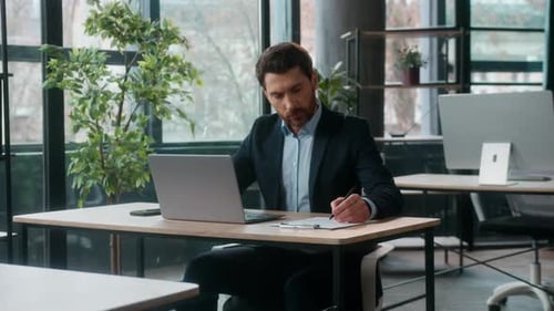 Confident Caucasian Businessman Writing Tasks Notes Working on Laptop in Office Successful