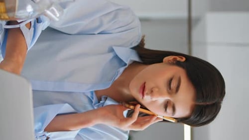 Woman Working on Laptop and Talking on Phone