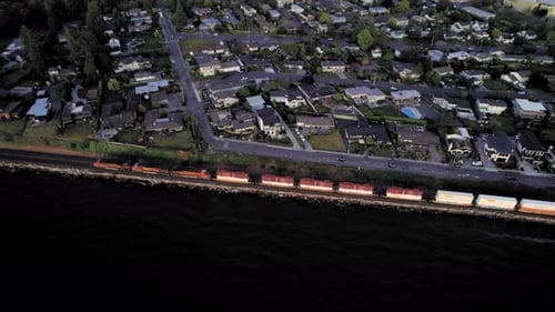 Drone Looking Down On Evening Train Passing Coastal Town