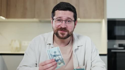 Smiling Man Holds and Fans Money in Kitchen