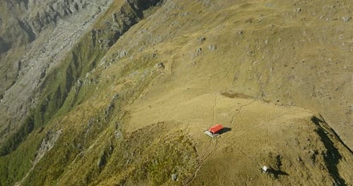 Mountain cabin on grass plateau in New Zealand alpine landscape, Brewster Hut
