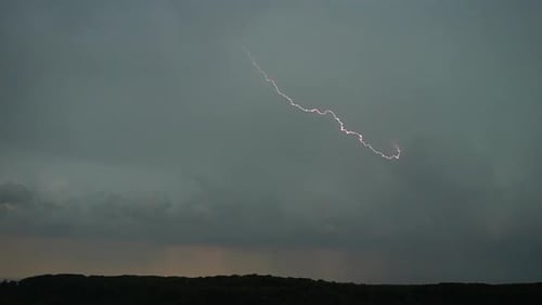 Flashes of lightning in the night sky among thunderclouds.