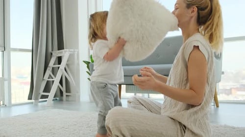 Mother and Child Playing with a Pillow Indoors