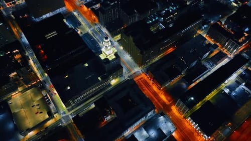Flying over the well-lit streets of a city with few cars moving by.