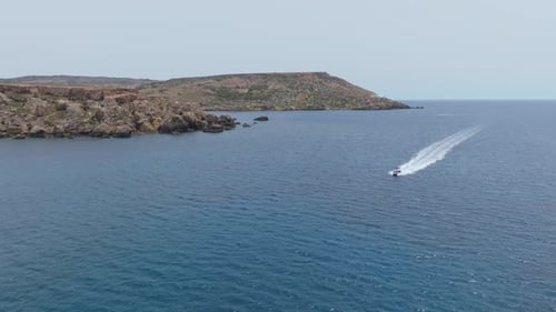 Speedboat Leaving Wake In The Calm Blue Ocean On A Sunny Day In Malta. - wide shot