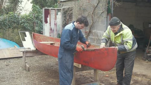 Mastercraftsman ensinando um aprendiz de conserto de barcos