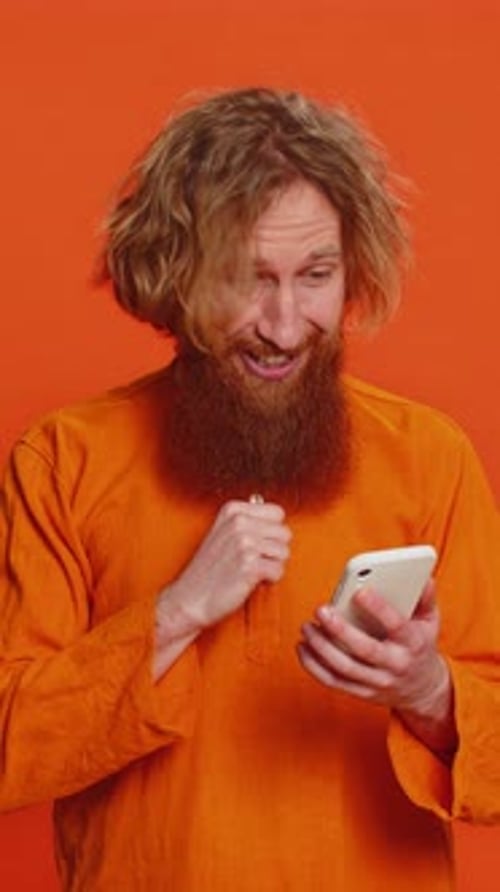 Man Celebrates Using Phone Against Orange Background