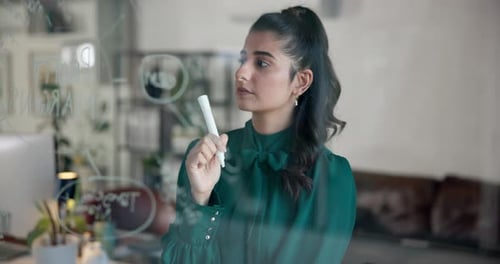 Woman Writing on Glass Wall in Bright Office
