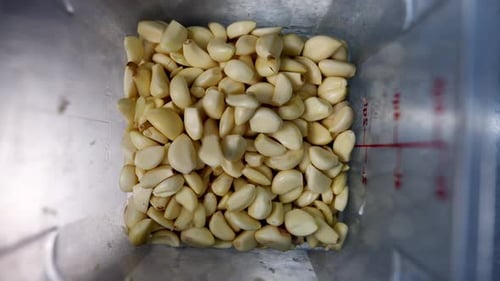 Dientes de ajo cayendo en una taza medidora